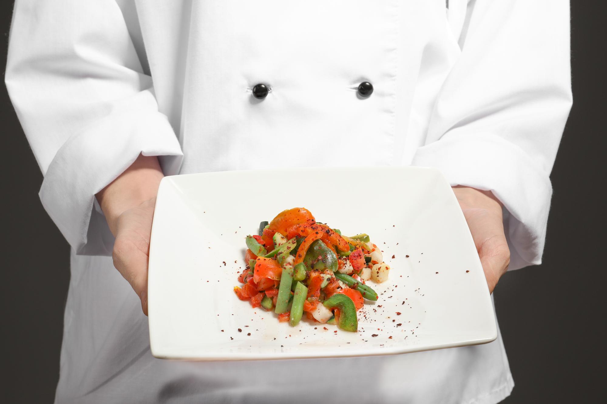 Instructor plating a dish in warm studio light